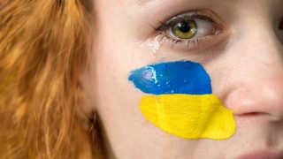 Crying woman with national flag of Ukraine on her cheek